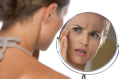 Frau sieht porige Haut im Spiegel